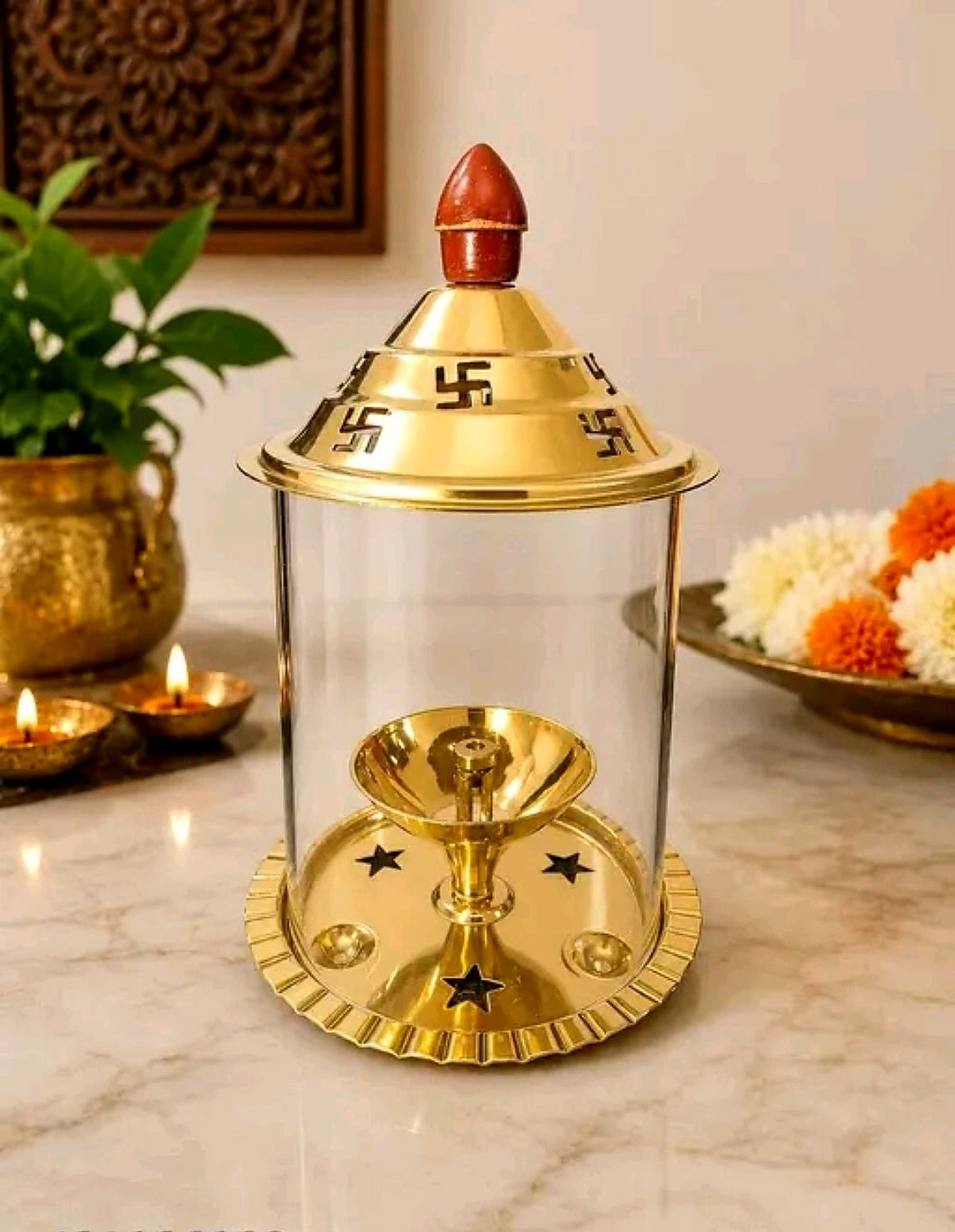 Main product image of gold-finish Akhand Jyoti lamp with clear glass enclosure and swastika motifs