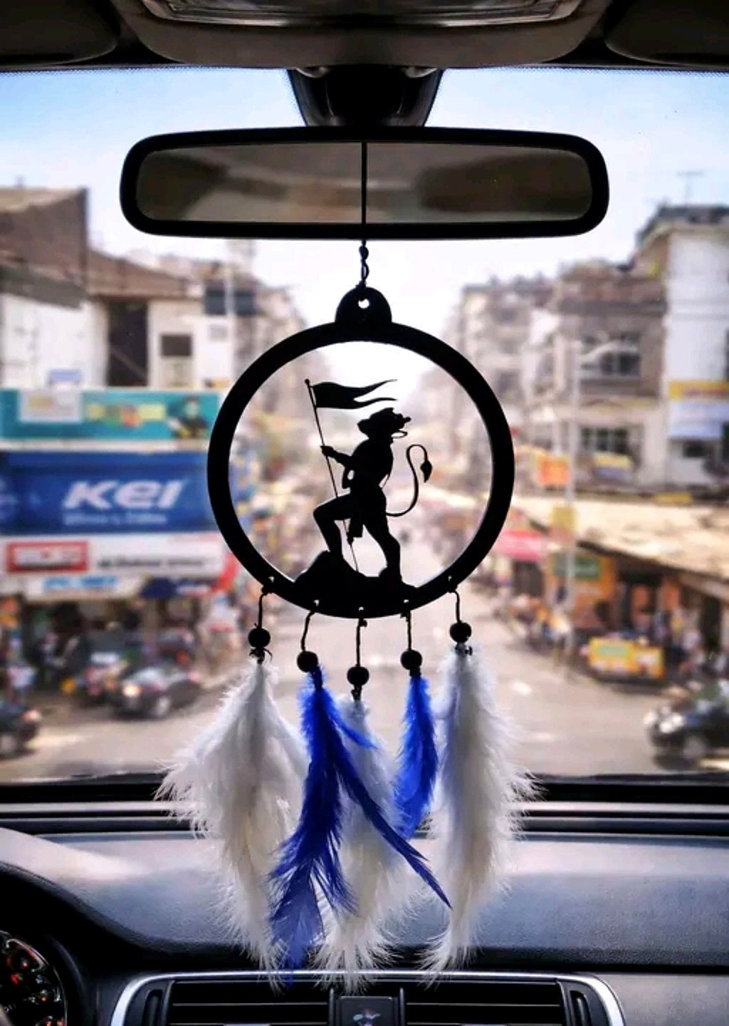 Hanuman flag silhouette car hanging displayed beneath the rear-view mirror in a city setting