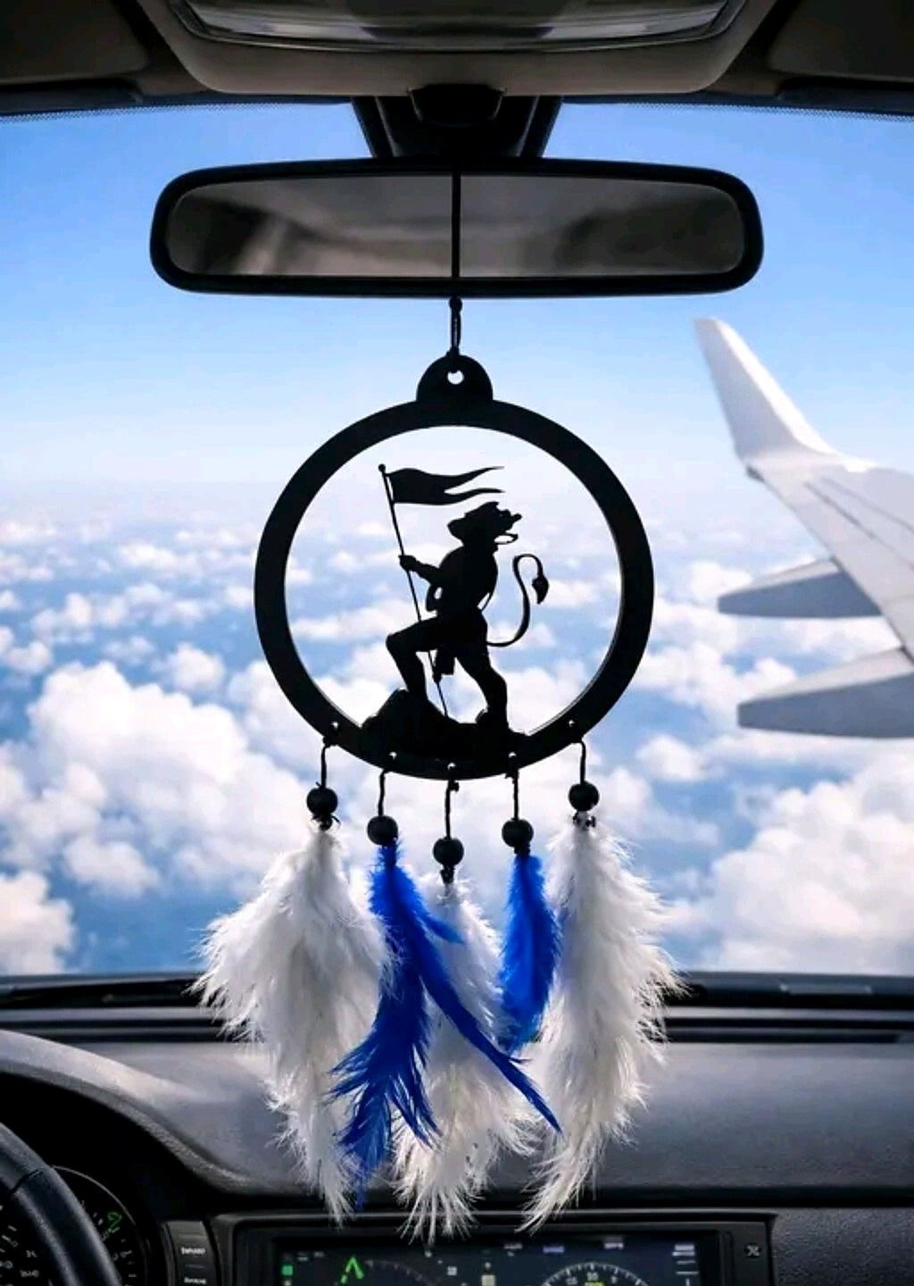 Hanuman flag silhouette hanging with blue and white feather tassels against a temple backdrop