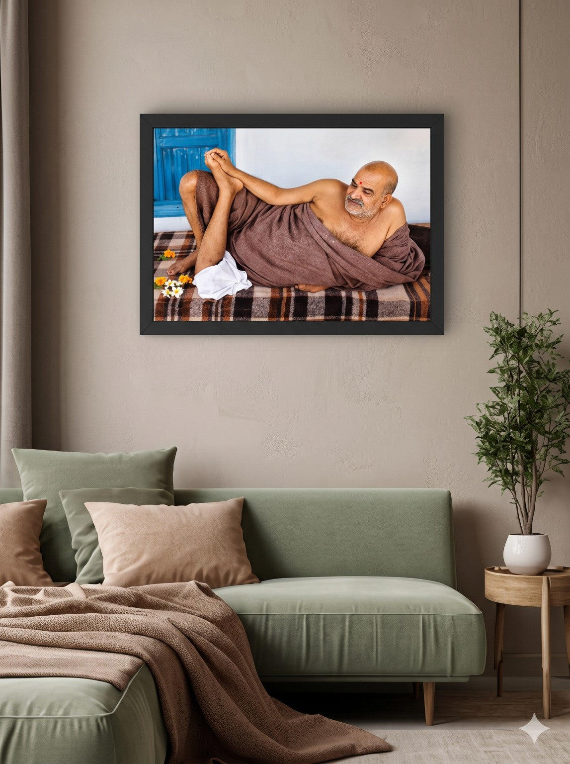Neem Karoli Baba reclining portrait displayed in a black landscape photo frame above a sofa